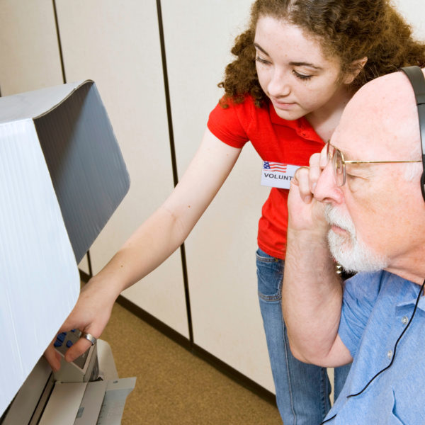 Teens helps senior at polling place.